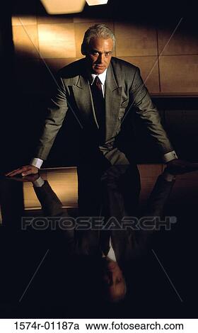 Senior businessman looking at camera while leaning forward on table View Large Photo Image Stock Image - Senior businessman looking at camera while leaning forward on table. Fotosearch