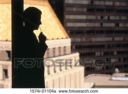 Stock Image - Silhouette of a businessman standing beside a window. Fotosearch