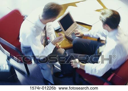 Two businessmen sitting in front of a laptop View Large Photo Image Stock Image - Two businessmen sitting in front of a laptop. Fotosearch