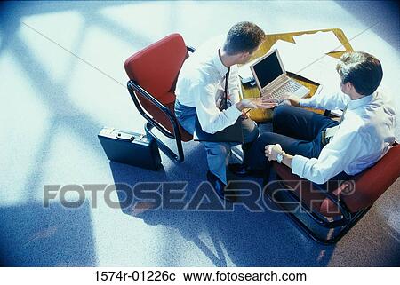 Two businessmen sitting in front of a laptop View Large Photo Image Stock Image - Two businessmen sitting in front of a laptop. Fotosearch