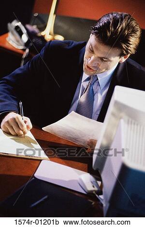 Stock Image - Young businessman making notes on his desk. Fotosearch