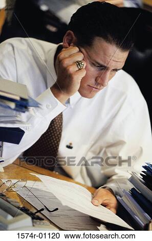 Young businessman reading a document on his desk View Large Photo Image Stock Image - Young businessman reading a document on his desk. Fotosearch