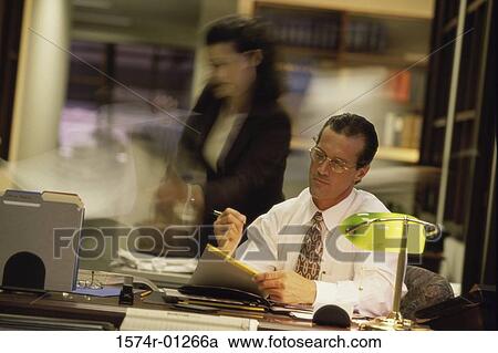 Stock Image - Young businessman reading documents at his desk. Fotosearch