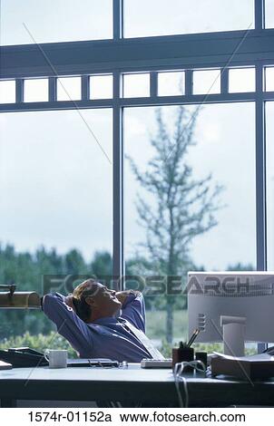 Stock Image - Young businessman reclining in his seat. Fotosearch