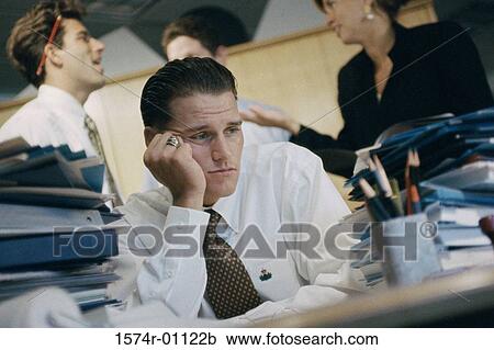 Young businessman sitting at his desk at work View Large Photo Image Stock Image - Young businessman sitting at his desk at work. Fotosearch