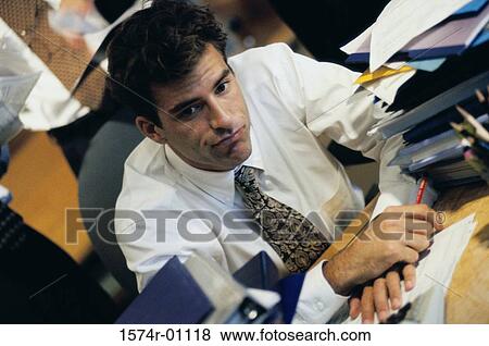 Young businessman sitting at his desk at work View Large Photo Image Stock Photo - Young businessman sitting at his desk at work. Fotosearch