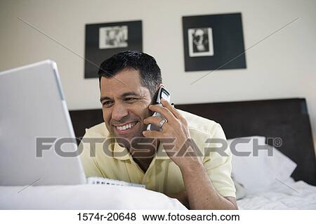 Close-up of a mature man using a laptop while talking on a mobile phone View Large Photo Image Stock Photo - Close-up of a mature man using a laptop while talking on a mobile phone. Fotosearch
