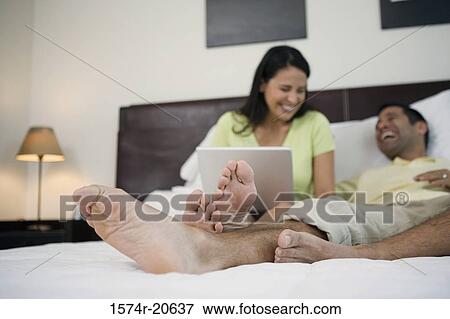 Mature man lying in the bed with a mature woman sitting beside him with a laptop on her lap View Large Photo Image Stock Photo - Mature man lying in the bed with a mature woman sitting beside him with a laptop on her lap. Fotosearch