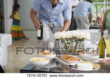 Mature man standing near a mature woman holding a wine bottle View Large Photo Image Stock Image - Mature man standing near a mature woman holding a wine bottle. Fotosearch