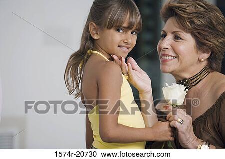Stock Image - Portrait of a girl giving a flower to her grandmother. Fotosearch