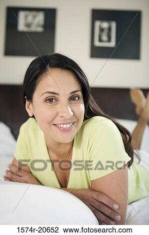 Stock Image - Portrait of a mature woman lying in the bed and smiling. Fotosearch