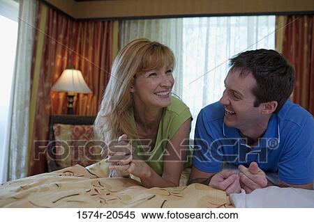 Close-up of a young couple lying on the bed and smiling View Large Photo Image Stock Photography - Close-up of a young couple lying on the bed and smiling. Fotosearch