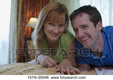 Portrait of a young couple lying on the bed and smiling View Large Photo Image Stock Photograph - Portrait of a young couple lying on the bed and smiling. Fotosearch