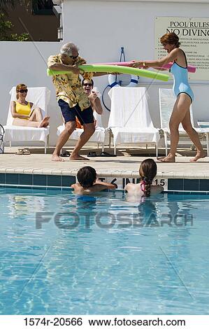 Stock Photograph - Side profile of a senior couple playing at poolside. Fotosearch
