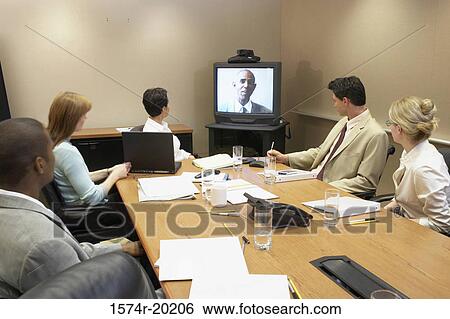 Business executives looking at the television in a video conference View Large Photo Image Stock Photograph - Business executives looking at the television in a video conference. Fotosearch