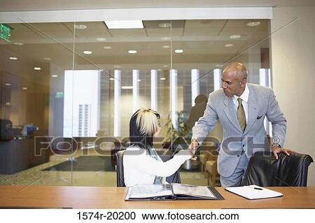 Businessman and a businesswoman shaking hands in an office View Large Photo Image Stock Image - Businessman and a businesswoman shaking hands in an office. Fotosearch