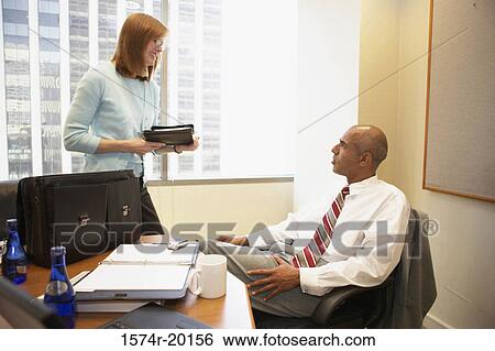 Businessman talking to his secretary in an office View Large Photo Image Stock Photograph - Businessman talking to his secretary in an office. Fotosearch