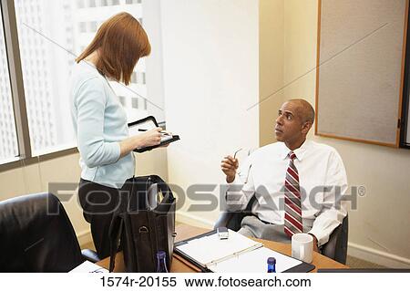 Stock Photography - Businessman talking to his secretary in an office. Fotosearch