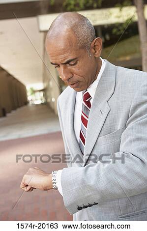 Close-up of a businessman looking at his wristwatch View Large Photo Image Stock Image - Close-up of a businessman looking at his wristwatch. Fotosearch
