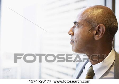 Close-up of a businessman looking through a window View Large Photo Image Stock Photo - Close-up of a businessman looking through a window. Fotosearch
