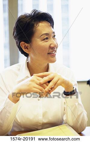 Stock Image - Close-up of a businesswoman sitting in an office and smiling. Fotosearch