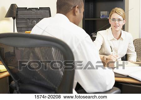 Rear view of a businessman and a businesswoman talking in an office View Large Photo Image Stock Photo - Rear view of a businessman and a businesswoman talking in an office. Fotosearch