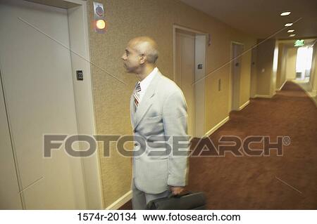 Side profile of a businessman holding his bag and standing in front of an elevator View Large Photo Image Picture - Side profile of a businessman holding his bag and standing in front of an elevator. Fotosearch