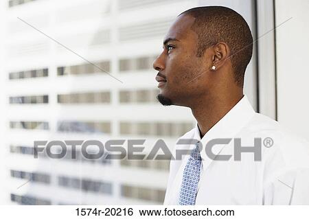 Side profile of a businessman looking through a window View Large Photo Image Stock Photograph - Side profile of a businessman looking through a window. Fotosearch