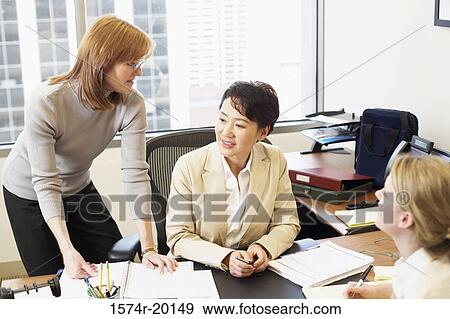Three businesswomen talking in an office View Large Photo Image Stock Photo - Three businesswomen talking in an office. Fotosearch
