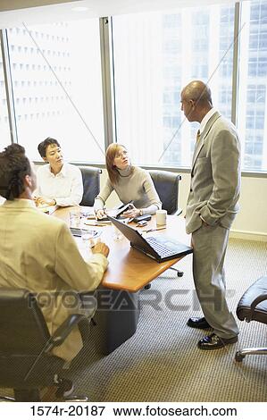 Stock Photo - Two businessmen and two businesswomen talking in a conference room. Fotosearch