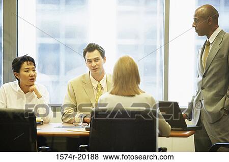 Stock Photo - Two businessmen and two businesswomen talking in a conference room. Fotosearch