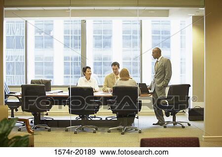 Stock Photo - Two businessmen and two businesswomen talking in a conference room. Fotosearch