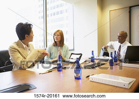 Two businesswomen and a businessman talking in a conference room View Large Photo Image Stock Image - Two businesswomen and a businessman talking in a conference room. Fotosearch