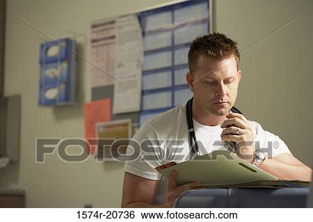 Stock Photograph - Close-up of a male doctor reading a document. Fotosearch