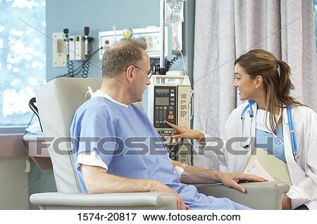 Female doctor operating an IV drip machine with a male patient looking at her View Large Photo Image Stock Photo - Female doctor operating an IV drip machine with a male patient looking at her. Fotosearch