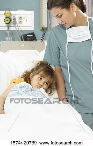 Girl lying on the bed and a female nurse standing beside her View Large Photo Image Stock Photo - Girl lying on the bed and a female nurse standing beside her. Fotosearch