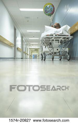 Low angle view of a male patient lying on a stretcher and holding a balloon View Large Photo Image Stock Photo - Low angle view of a male patient lying on a stretcher and holding a balloon. Fotosearch