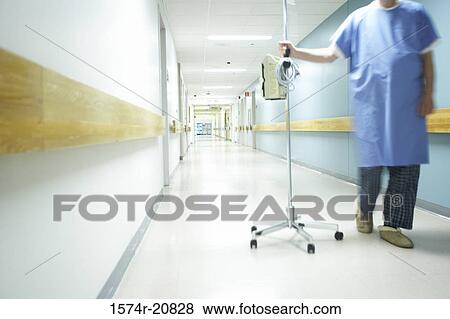 Stock Photo - Low section view of a male patient walking with an IV drip stand. Fotosearch