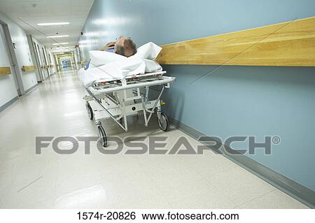 Male patient lying on a stretcher in the corridor of a hospital View Large Photo Image Stock Photograph - Male patient lying on a stretcher in the corridor of a hospital. Fotosearch