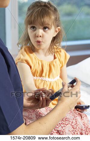 Stock Photo - Mid section view of a female nurse taking a blood sample from a girl's finger. Fotosearch