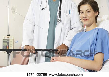 Stock Photograph - Portrait of a female patient smiling with a male doctor standing beside her. Fotosearch