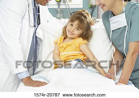 Portrait of a girl smiling with a female nurse and a male doctor standing beside her View Large Photo Image Stock Photo - Portrait of a girl smiling with a female nurse and a male doctor standing beside her. Fotosearch