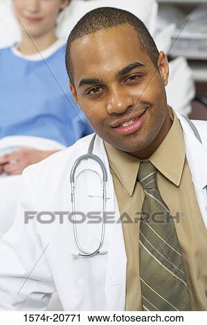 Portrait of a male doctor smiling with a female patient reclining on the bed behind him View Large Photo Image Stock Image - Portrait of a male doctor smiling with a female patient reclining on the bed behind him. Fotosearch