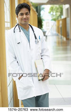 Stock Image - Portrait of a male doctor standing in a corridor. Fotosearch