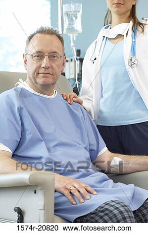 Portrait of a male patient sitting in an armchair and a female doctor standing beside him View Large Photo Image Stock Image - Portrait of a male patient sitting in an armchair and a female doctor standing beside him. Fotosearch