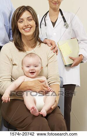 Portrait of a young woman holding her son with a female doctor and a mid adult man standing behind her View Large Photo Image Stock Image - Portrait of a young woman holding her son with a female doctor and a mid adult man standing behind her. Fotosearch