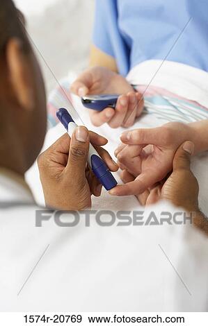 Stock Photo - Rear view of a male doctor taking a blood sample from a female patient's finger. Fotosearch