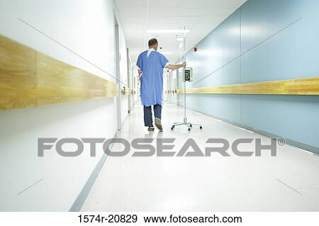 Rear view of a male patient walking with an IV drip stand View Large Photo Image Stock Photo - Rear view of a male patient walking with an IV drip stand. Fotosearch