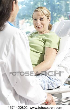 Stock Image - Side profile of a female doctor sitting in front of a pregnant woman. Fotosearch