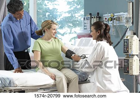 Stock Photo - Side profile of a female doctor checking the blood pressure of a pregnant woman. Fotosearch
